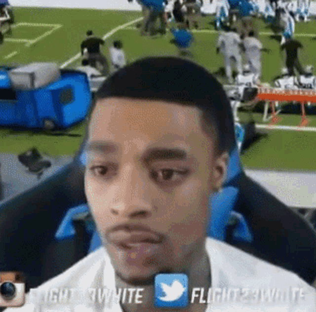 a man is sitting in front of a football field with a twitter icon in the corner