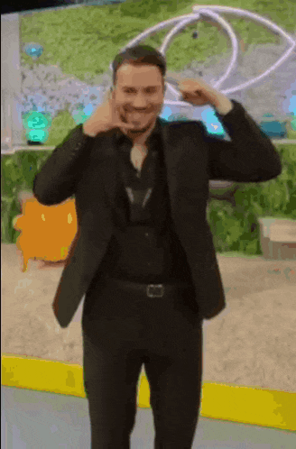 a man in a suit and black shirt is making a face