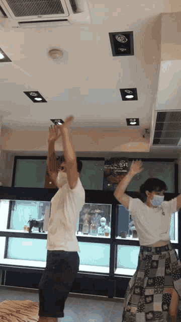 a man and a woman wearing face masks are dancing in a store