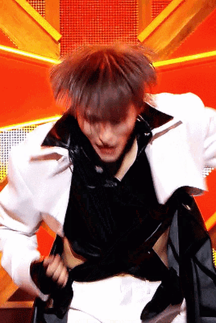 a man in a white jacket and black shirt is dancing on stage