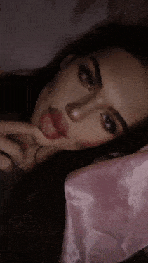 a woman sticking her tongue out while laying on a pink blanket