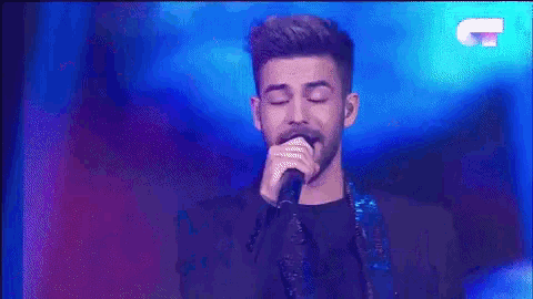 a man with a beard singing into a microphone on a stage