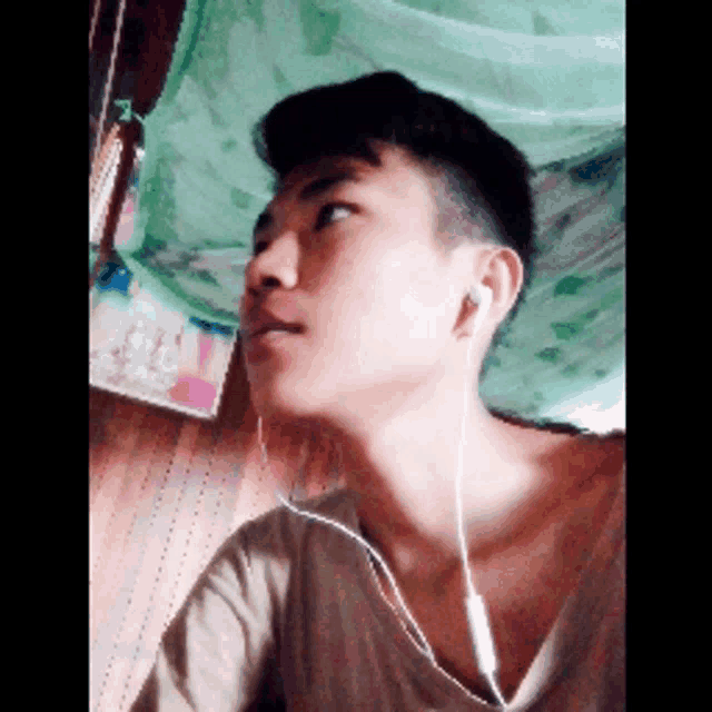a young man wearing ear buds looks up at something