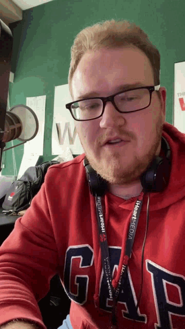 a man wearing glasses and a red gap shirt