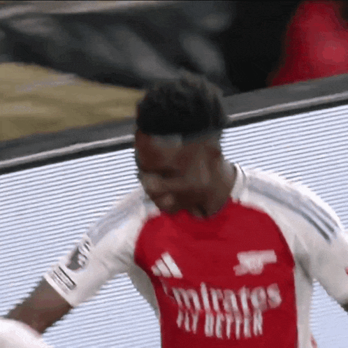 a soccer player wearing a red and white emirates fly better jersey