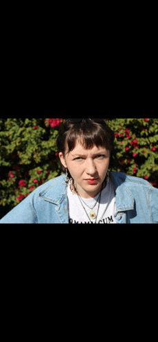 a woman wearing a denim jacket and a t-shirt that says " okay cum "