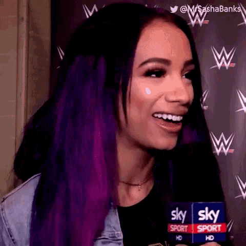 a woman with purple hair is smiling while holding a microphone .