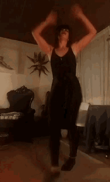 a woman is dancing in a living room in front of a chair