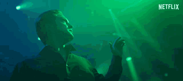 a man in a green shirt is dancing in front of a green background that says netflix on it