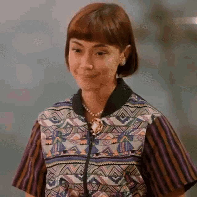 the woman is wearing a colorful jacket and a necklace .