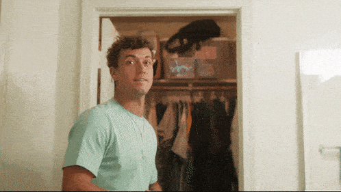 a man in a blue shirt stands in front of a closet