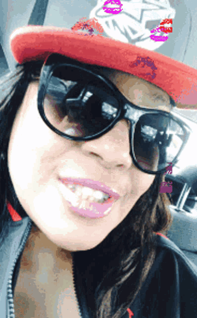 a woman wearing sunglasses and a red hat has a kiss on her hat