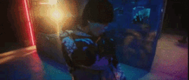 a person is standing in front of a fish tank in a dark room with a lot of lights .