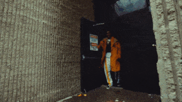 a man in a yellow coat stands in front of a door with a danger sign
