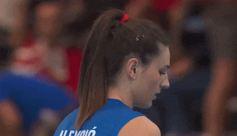 a female volleyball player wearing a blue jersey is looking down at something .