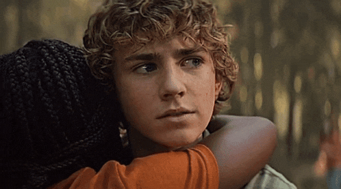 a boy with curly hair is being hugged by a woman
