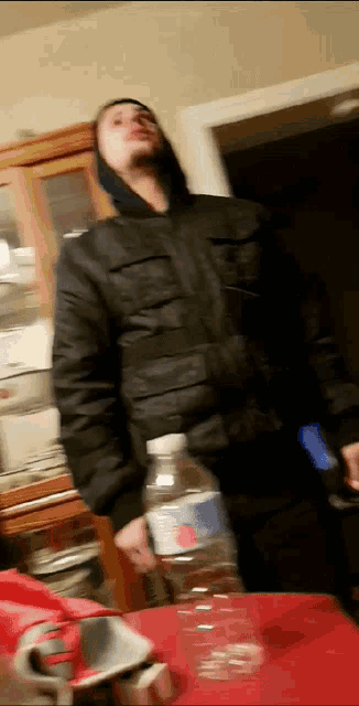 a man in a black jacket is holding a pepsi water bottle