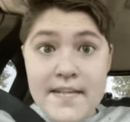 a close up of a person 's face in a car with a blurred background .