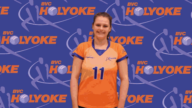 a woman wearing a number 11 jersey stands in front of a holyoke background