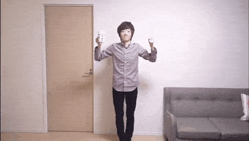 a man in a plaid shirt is holding a remote control in front of a couch
