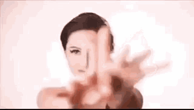 a woman is making a peace sign with her hands while standing in front of a white background .