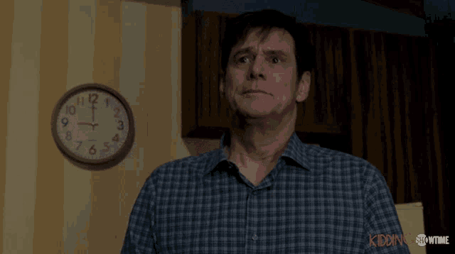 a man in a plaid shirt stands in front of a clock that says showtime on it