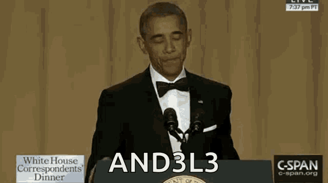 a man in a tuxedo stands at a podium with the words and3l3 on it