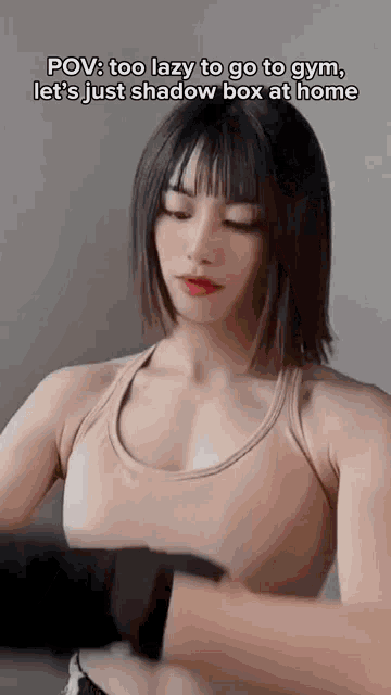 a woman is lifting a dumbbell in a gym while wearing a tank top .