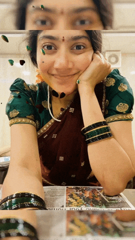 a woman wearing a green blouse is smiling while looking at a magazine