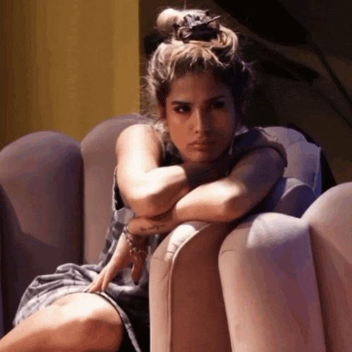 a woman is sitting on a couch with her head resting on her arm