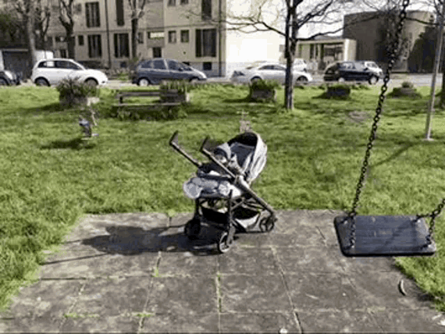 a stroller with a baby in it is sitting next to a swing in a park .