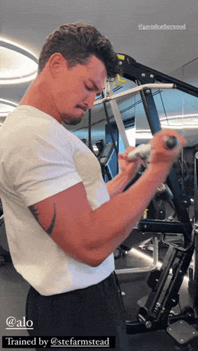 a man in a white t-shirt is using a machine in a gym with the caption trained by @stefarmstead