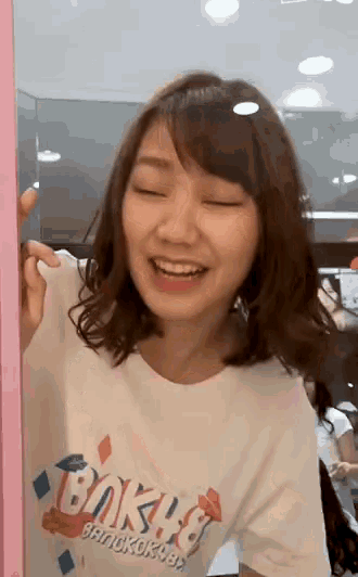 a woman wearing a white t-shirt that says baka on it is smiling