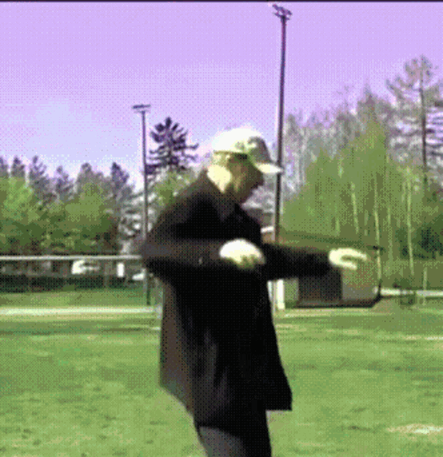a man in a baseball cap and jacket is dancing in a field