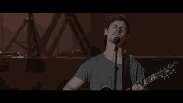 a man singing into a microphone with his eyes closed