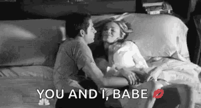 a man and a woman are sitting on a bed kissing .