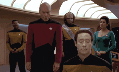 a group of people are standing in a room and one of them has a star trek uniform on