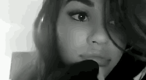 a black and white photo of a woman 's face with her mouth open .
