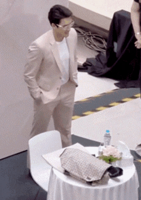 a man in a suit is standing next to a table