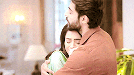 a man is hugging a woman in a living room in a room .