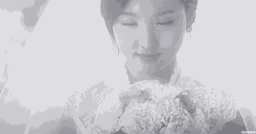 a woman in a wedding dress is holding a bouquet of flowers in a black and white photo .