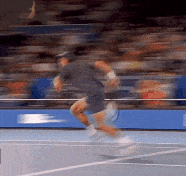 a man is running on a tennis court with a racket in his hand