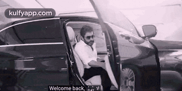 a man is getting out of a car with the door open and a welcome back message .