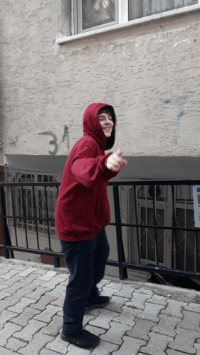 a person wearing a red hoodie stands in front of a wall with the number 31 written on it