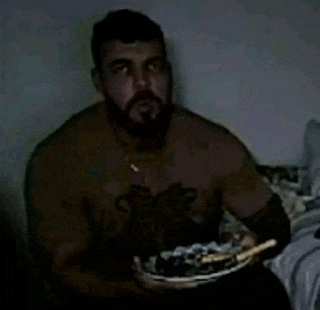 a man with a beard is holding a plate of food in his hand