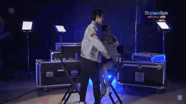 a man and woman are hugging in front of a sign that says kapamilya