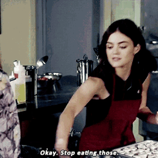 a woman in an apron says " okay stop eating those " in a kitchen