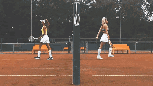 two women are playing tennis on a court and one is wearing a yellow top