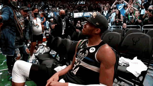 a basketball player wearing a number 14 jersey sits in the stands