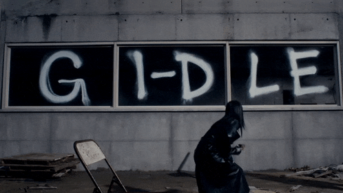 a person standing in front of a wall that says g1-dle